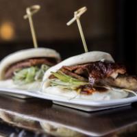 Crispy Duck Steamed Buns · Duck with scallions and hoisin sauce inside a steamed bun. Includes two pieces.