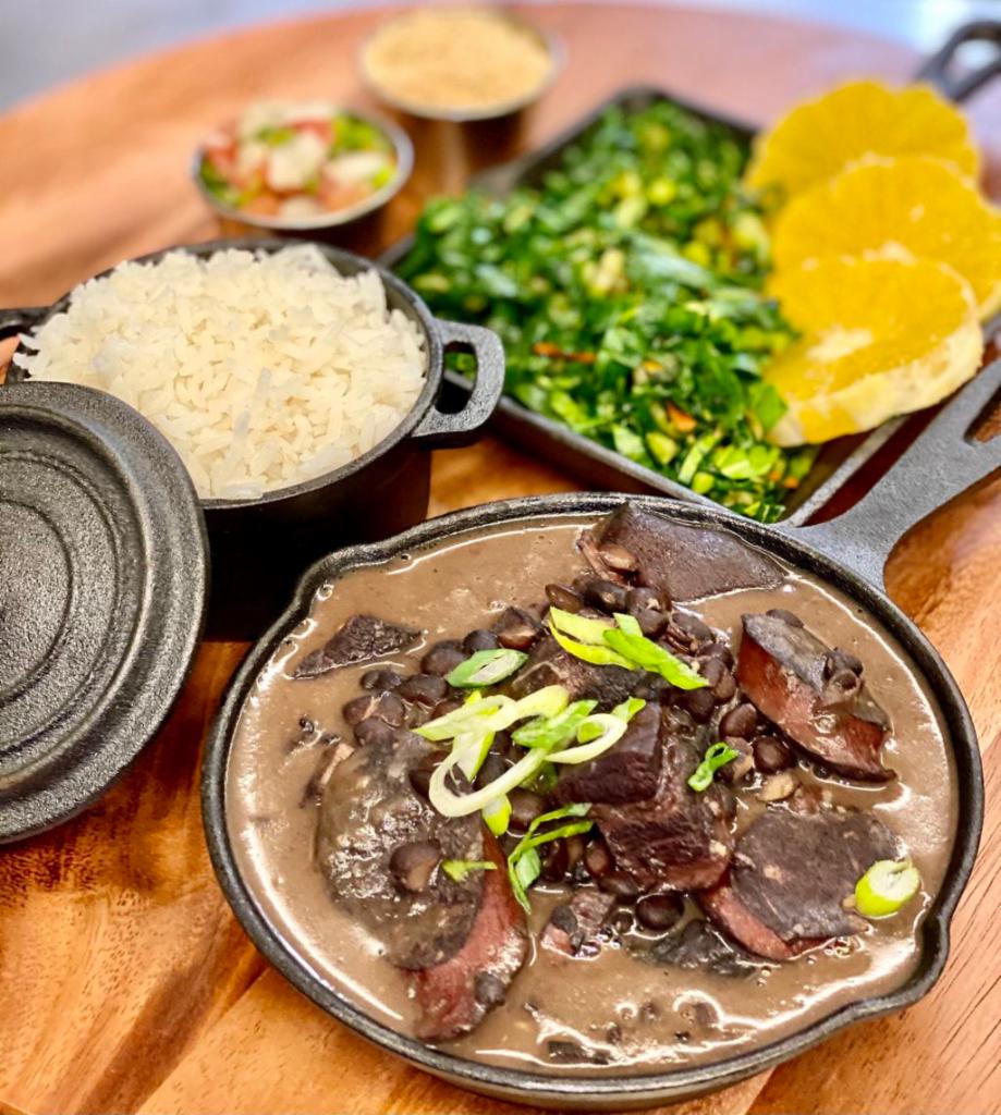 Feijoada for One · Feijoada (black beans stew with dry beef, pork sausage, pig feet and bacon) Served with Rice, vinaigrette, seasoned yuca flour, collard greens and orange slices. 