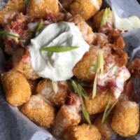 Loaded Tots · Tater tots smothered in white cheddar cheese sauce, bacon, green onions, and sour cream.
