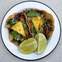 Al Pastor Taco · Marinated pork with onion, cilantro, and a slice of pineapple.

