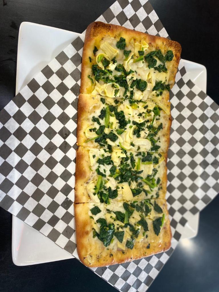 White Spinach and Artichoke Flatbread · Made with a base of our garlic white sauce topped with spinach, artichokes and mozzarella cheese.