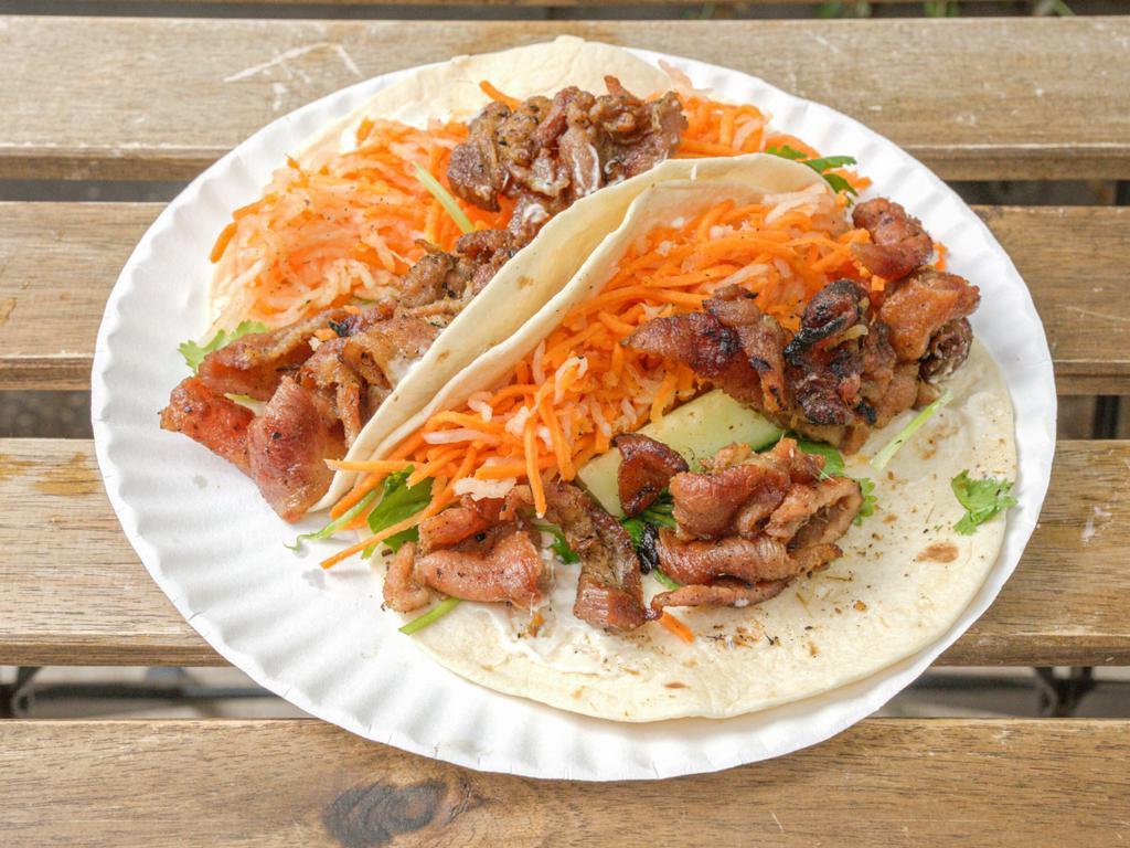 Grilled Pork Tacos · Vietnamese style marinated pork in 2 soft corn tortillas with butter, mayo, crispy pickled carrot, daikon radish, cucumber and cilantro.