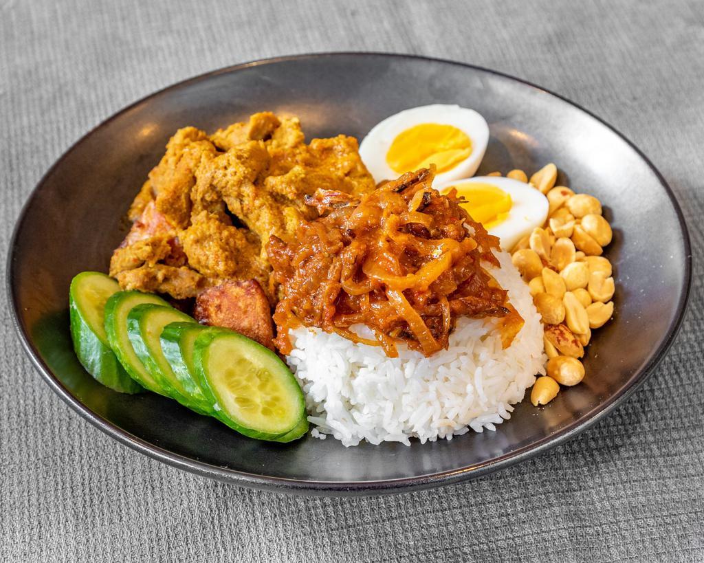 Nasi Lemak · Traditional Malaysian dish consisting of curried chicken, served alongside rice topped with peanuts, boiled egg, cucumber and sauteed onions with anchovy.