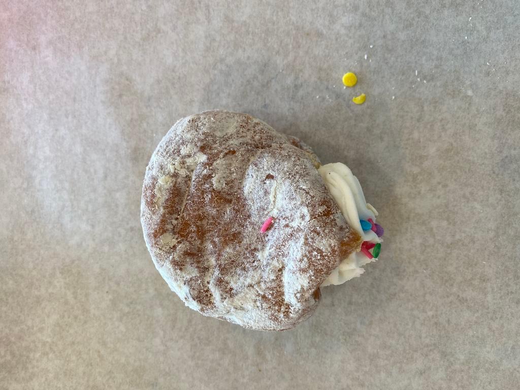 Vanilla Cream Donut · Raised donut coated in powdered sugar, filled with vanilla cream, and topped with sprinkles