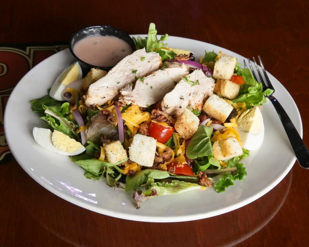 Saloon Salad · A large portion of mixed greens with choice of dressing, tomatoes, diced red onions, black olives, ham, bacon bits, and shredded cheddar. Garnished with a hard-boiled egg and croutons.