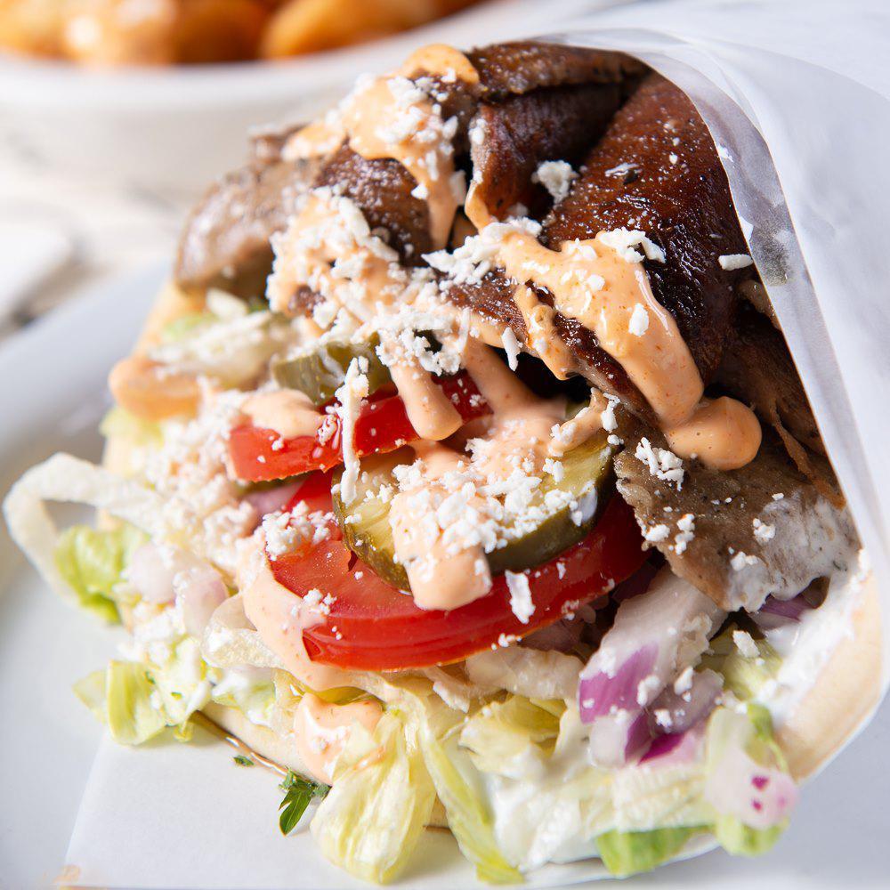 Spicy Lamb Gyro with Feta · Slow roasted lamb and beef sliced and seasoned with our special Mediterranean spices with lettuce, tomatoes, pickles and onions, topped with feta cheese and spicy garlic sauce and wrapped in a soft, warm pita.