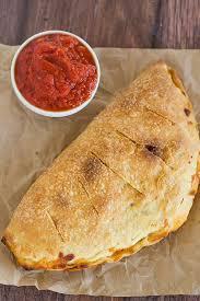 Traditional Calzone · Ham, ricotta cheese and mozzarella cheese. Served with garlic sauce and traditional tomato s...