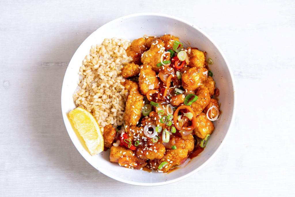 Orange Chicken 2.0 · Antibiotic-free, oven-fried chicken with charred peppers, caramelized onions, green onions, sesame seeds, and our house-made orange sesame sauce. Served with a lemon wedge, and a base of your choice. (gluten-free)