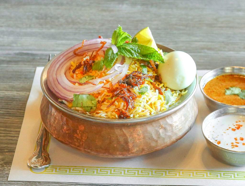 Hyderabadi Chicken Dum Biryani · Long grain basmati rice flavored with saffron is cooked in a traditional Hyderabadi style with a delicate blend of exotic spices and herbs, along with pieces of chicken. Served with raita and salan.