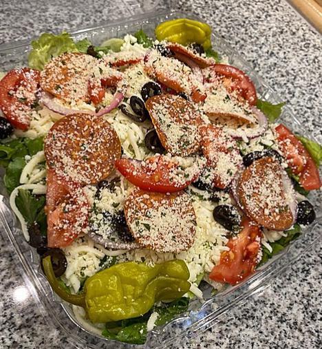 Italian Salad · A large bed of romaine lettuce, tomatoes, black olives, red onions, cheese, pepperoni and pepperoncini. Served with your choice of our house made dressing: creamy garlic, Italian or ranch. Gluten Free.