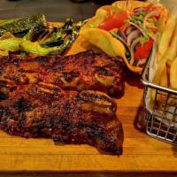 Costillas de Res a la Parrilla · Grilled beef short ribs with french fries and avocado salad.