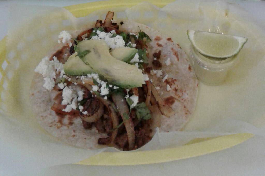 Monster taco · Home made Tortilla  beef fajita with grilled onions on top  covered with white Mexican queso fresco and avocado.  