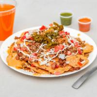 Nachos · Tortilla chips covered in nacho cheese and topped with ground beef, pinto beans, tomatoes, o...