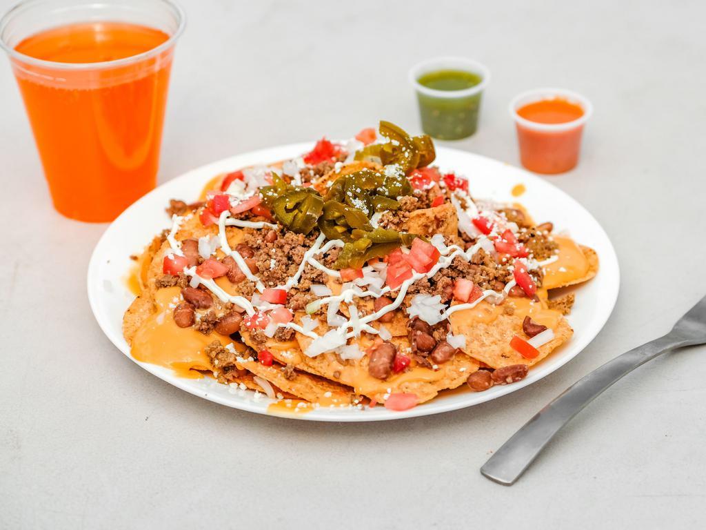 Nachos · Tortilla chips covered in nacho cheese and topped with ground beef, pinto beans, tomatoes, onions, sour cream, cotija cheese and jalapenos.
