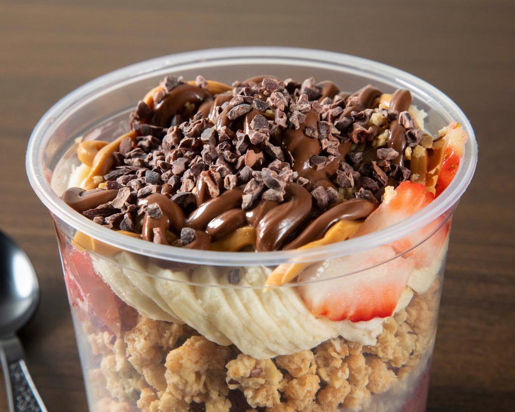 Uppers Bowl · Always worth the journey. The uppers bowl is packed with organic blueberry flax seed granola, organic peanut butter swirled acai, banana,strawberries topped with more peanut butter, nutella and cocoa nibs.