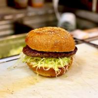 Classic Hamburger · Black Angus burger with lettuce, tomato, and onion on a hamburger bun.