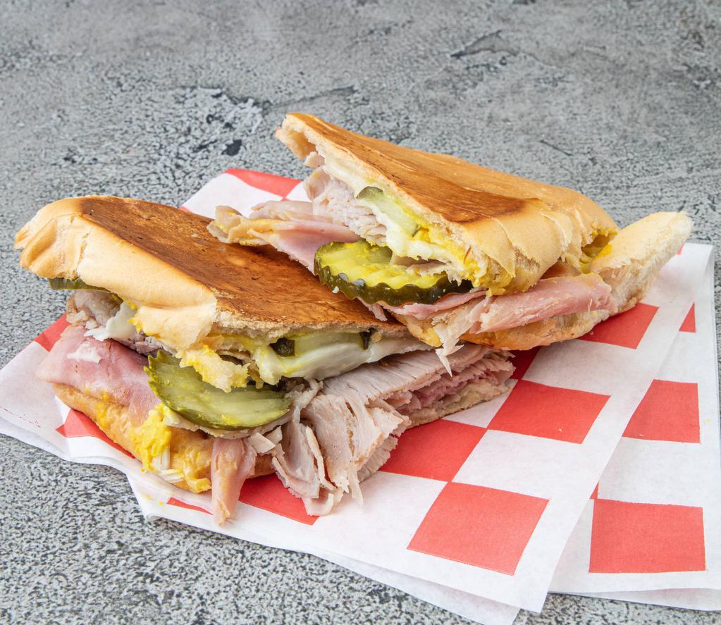 The Cuban Cuban Sub · Freshly sliced deluxe ham, sliced pork, and melted Austrian Swiss. Topped with pickles, mustard and finally grilled.