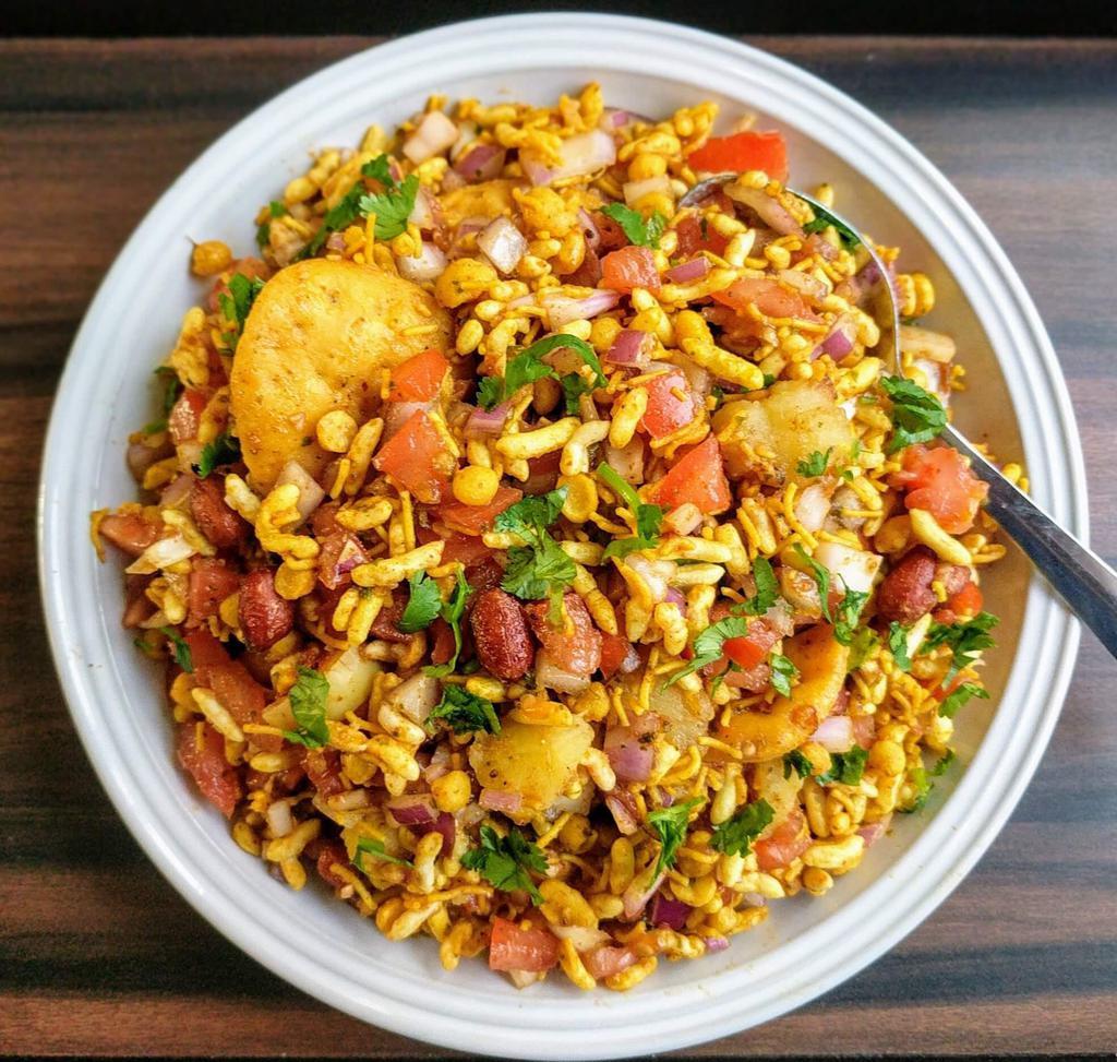 Bhel Poori Bhel · Puffed rice tossed with fresh herbs, onions, and tomatoes. Topped with tamarind and cilantro chutney.
