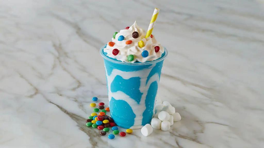 Cotton Candy Shake · Cotton candy ice cream topped with whipped cream and m&m, with marshmallow topping drizzle on the side of the cup.