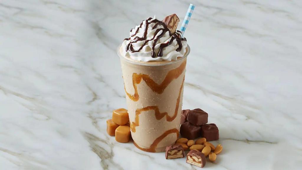 Snickers  · Sweet cream ice cream mixed with snickers topped with whipped cream and carmel drizzle on top and the side of the cup.