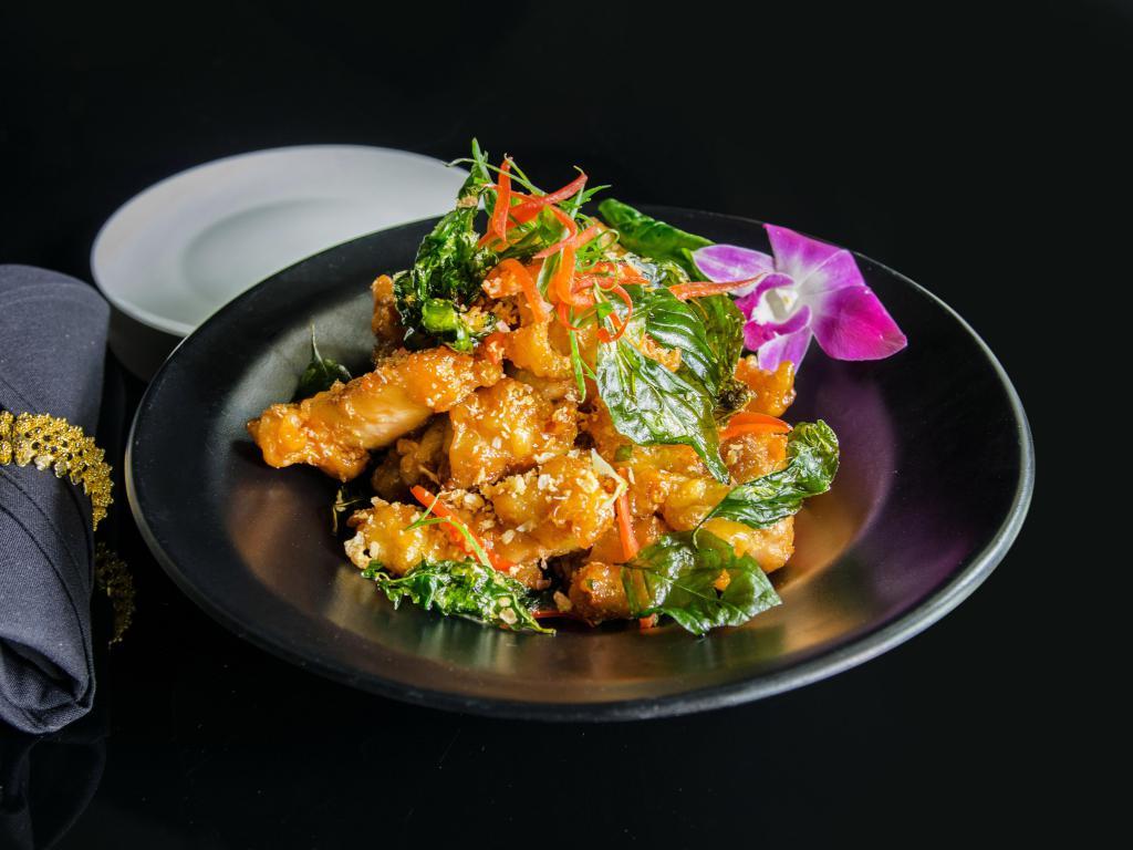 Crispy Garlic Chicken · Our house specialty. Lightly battered and fried boneless chicken pieces, stir-fried in a sweet, garlic-infused sauce topped with crispy fried basil leaves and red bell peppers.