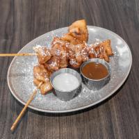 Cinny-Bobs · 2 skewers of fried cinnamon roll dough with white icing and caramel to dip.