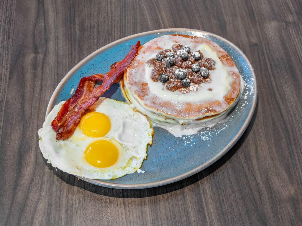 #16 · 3 blueberry pancakes, lemon glaze, cream cheese and streusel topping. Served with 2 strips of bacon and choice of eggs.