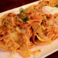 Shredded Chicken Nachos · Tortilla chips topped with melted cheese and refried beans. Served with pico de gallo and so...