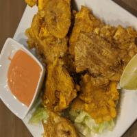 Tostones · Green deep-fried plantains, served with a side of salsa Rosada.