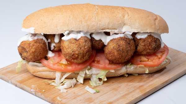 Woe Po Boy · Our spin on boudin balls a Louisiana classic. Fresh crisp lettuce, sliced to order tomatoes, topped with a drizzle of our remoulade sauce. All this goodness resting in between freshly sliced Leidenheimer bread. I dare you to fit a pair in your mouth.