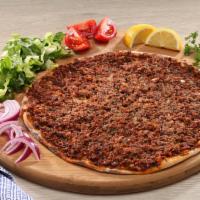 Lahmajoun · Lahmacun is a round, thin piece of dough topped with ground beef, minced vegetables, and her...