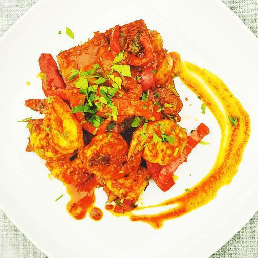 Smoked Paprika and Tomato Prawns · Spicy jumbo prawns, sautéed with onions, peppers, cherry tomatoes, and fresh herbs in a smoked paprika tomato sauce over a fried polenta cake.
