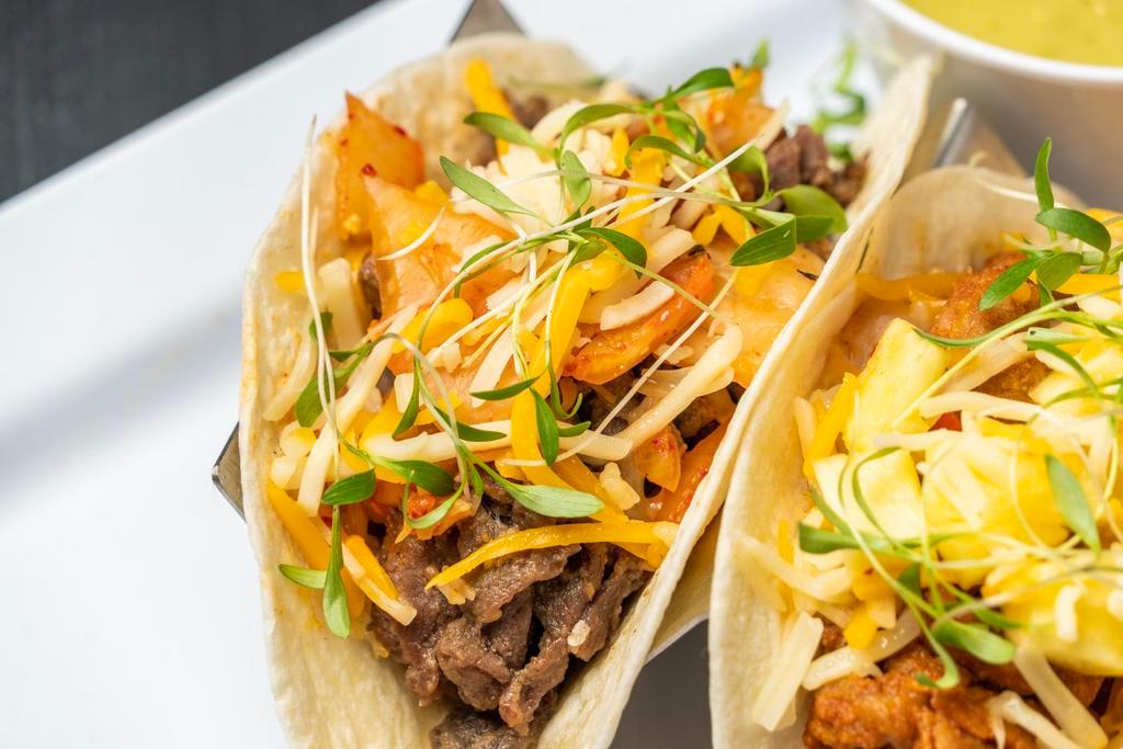 Bulgogi (Ribeye) Taco · Thinly sliced Ribeye in a sweet soy based marinade, green onions, white onions, and garlic.  Topped with Kimchi, Cheese, TaKorea Greens, Cilantro, and your choice of sauce/salsa on the side.  Served in our Gordita crunch taco shell
