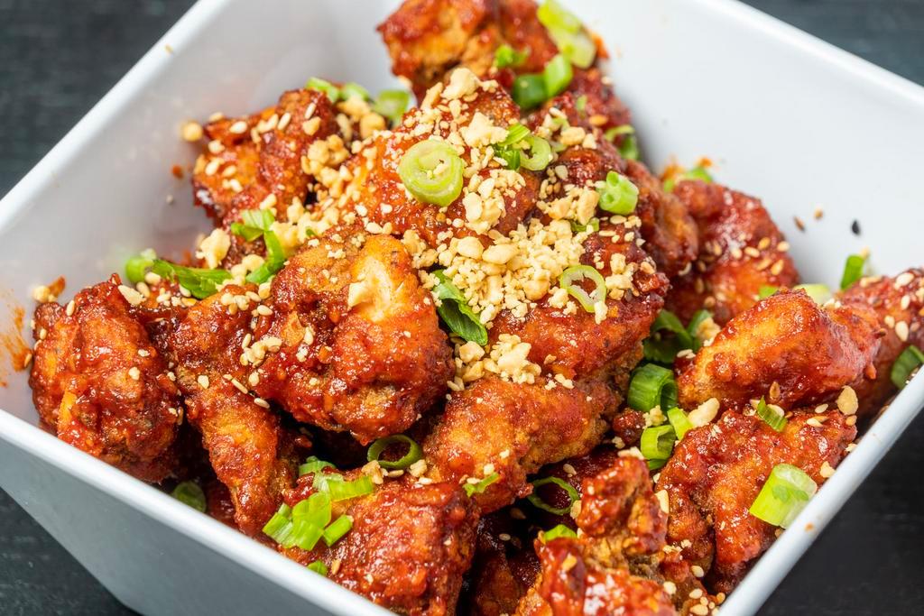 Korean Fried Chicken · Crispy double-fried chicken coated with spicy Korean sauce, topped with crushed peanuts, white and black sesame seeds, and chopped green onion.