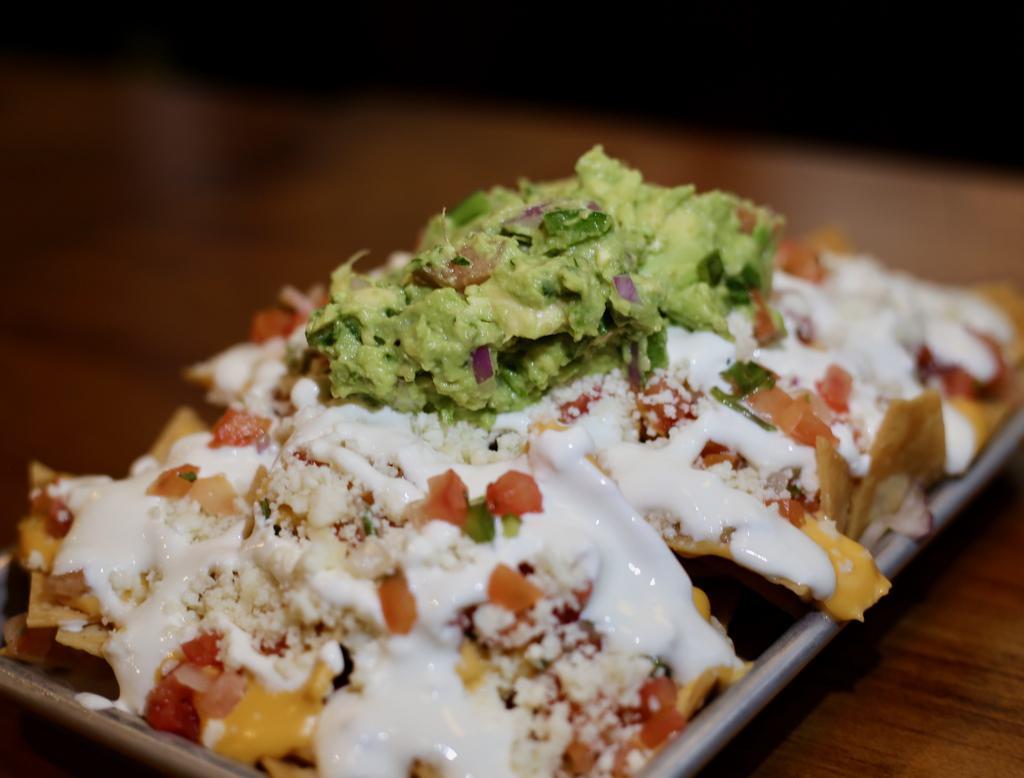 Nachos · House-made tortilla chips, cheese sauce, pico de gallo, queso fresco, guacamole. Add toppings for an additional charge.