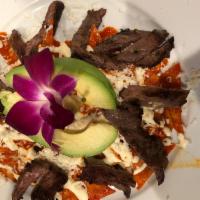 Chilaquiles Rojos · Corn tortilla lightly fried with skirt steak in guajillo sauce with onions. Mexican cream an...