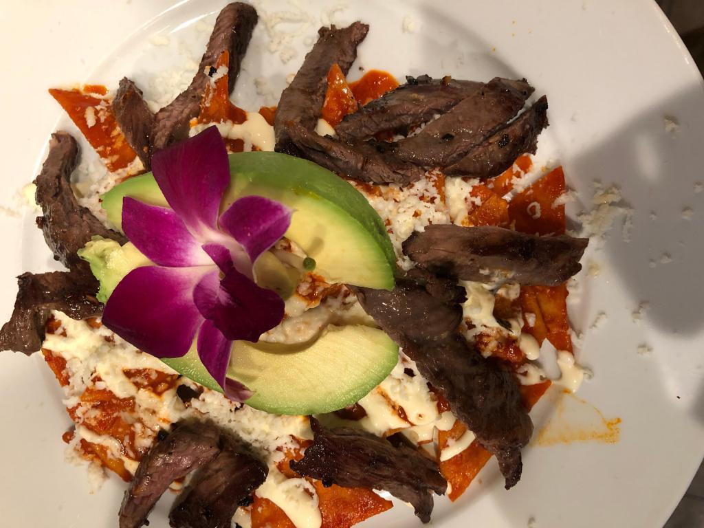 Chilaquiles Rojos · Corn tortilla lightly fried with skirt steak in guajillo sauce with onions. Mexican cream and queso fresco.