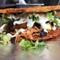 Shredded Chicken Patacon · Smashed green plantain sandwich stuffed with shredded chicken, fried queso blanco, green lea...