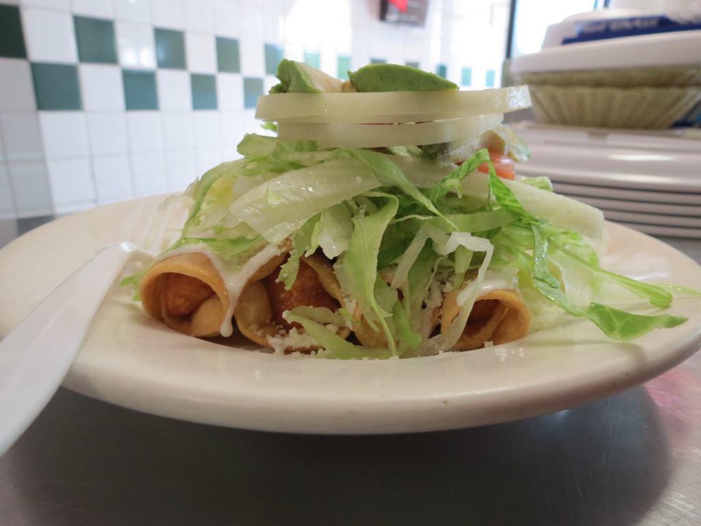 Flautas de Pollo · Hard-shelled fried tacos filled with chicken topped with sour cream, cheese, onion, tomato, and avocado.