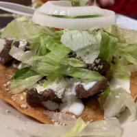 Tostadas con Carne · Fried tortilla topped with sour cream, cheese, lettuce and your choice of meat.