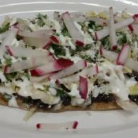 Huarache de Bistec · Oval real corn tortilla topped with refried beans, meat of choice, lettuce, Cotija cheese an...
