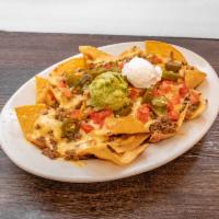 Classic nachos · Tortilla chips smothered with refried bean, three blend cheese and Chile con queso. Topped w...