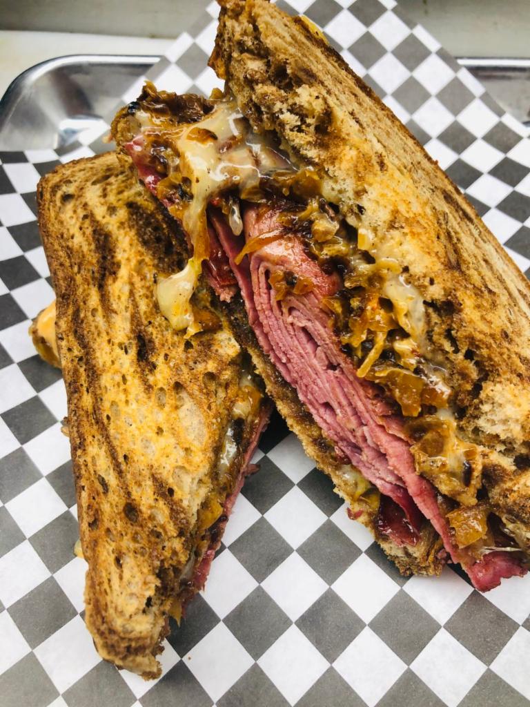 MKE Rueben Sandwich · Spotted cow braised corn beef, pepper jack and Swiss blend cheese, bacon kraut and boom boom sauce served on thick rye bread. Served with chive fries.