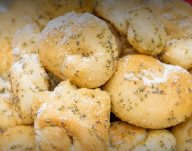 Garlic Knots · Bread, topped with garlic & olive oil or butter, herb seasoning, baked to perfection. Melts in your mouth and arouses the taste buds.
