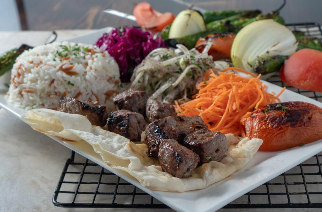 Tenderloin Kabab · Skewers of spiced, cubed tenderloin beef kabab grilled over charcoal served with grilled tomatoes, onions and peppers, onion-parsley salad and rice.