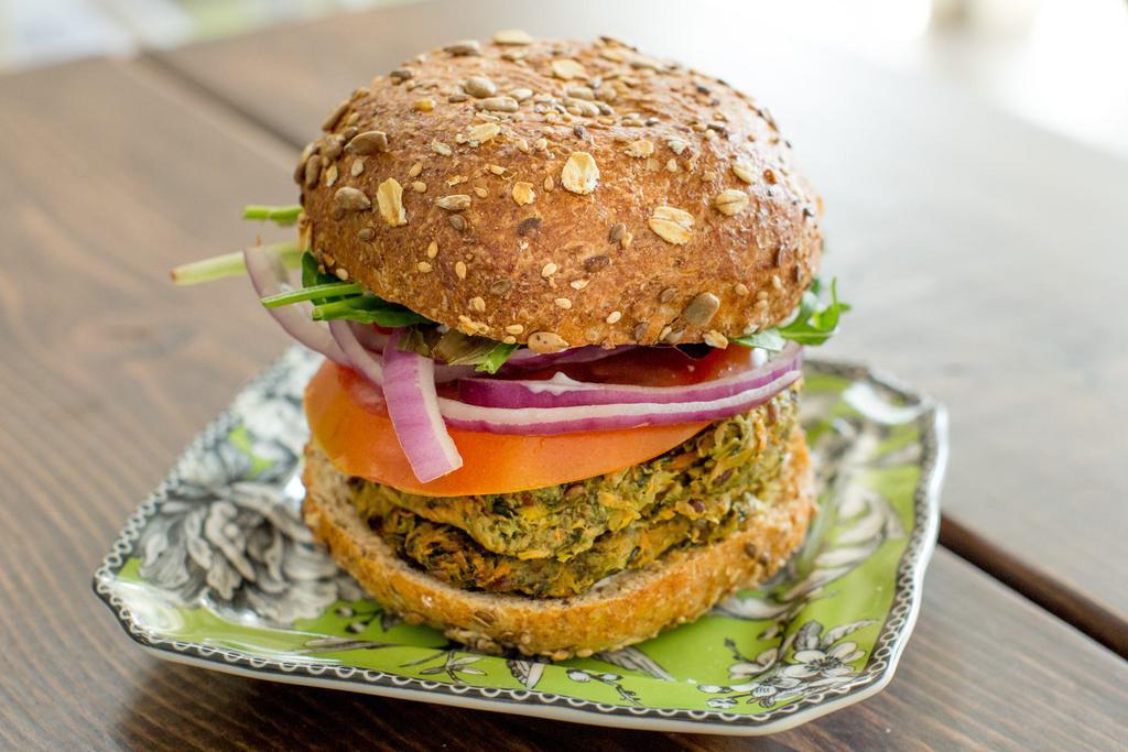 NEW RECIPE Harvest Veggie Burger (V) · 100% Organic Black Bean, Beet, Butternut squash, zucchini, carrot and sweet potato. Served on a bun with Fakin Bacon, Vegan Cheese, Baby greens, sprouts, onions, tomatoes, shredded carrots and veganaise. Harvest Patty is Vegan, Gluten-Free