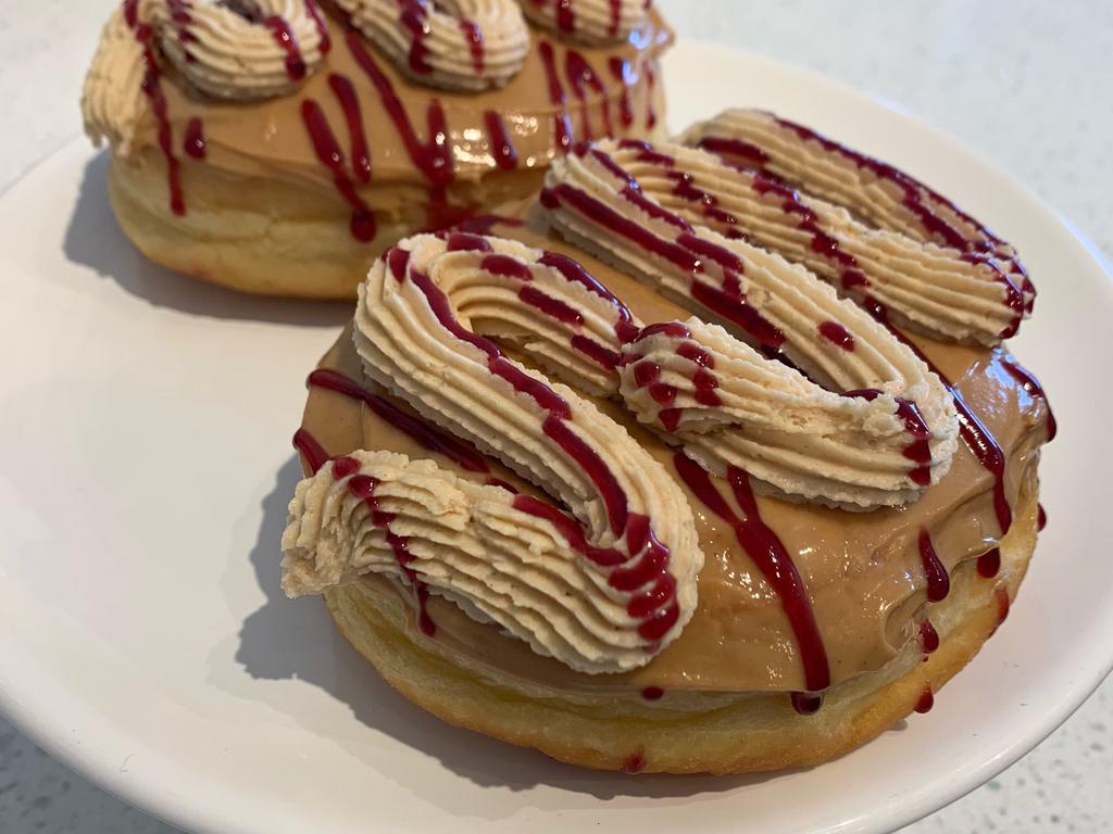 Peanut Butter Jelly Time · Yeast donut filled with black raspberry jelly, topped with peanut butter, peanut butter buttercream & drizzled with raspberry