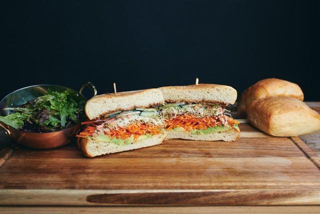 The Guac & Mole Sandwich · Avocado, vegan mole, clover sprouts, shredded carrots, cucumber, vegan ranch dressing, lemon vinaigrette, served on ciabatta. Vegan.