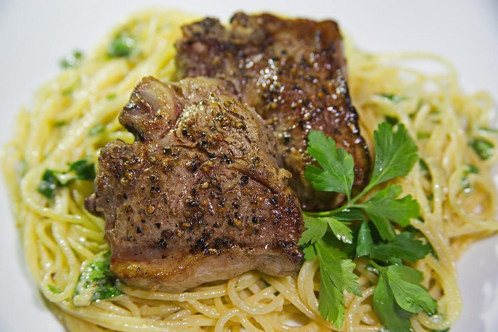 Lamb Chops · Grilled lamb chops served on spaghetti. Served with house salad and garlic bread. Garnished with Parmesan cheese and parsley.
