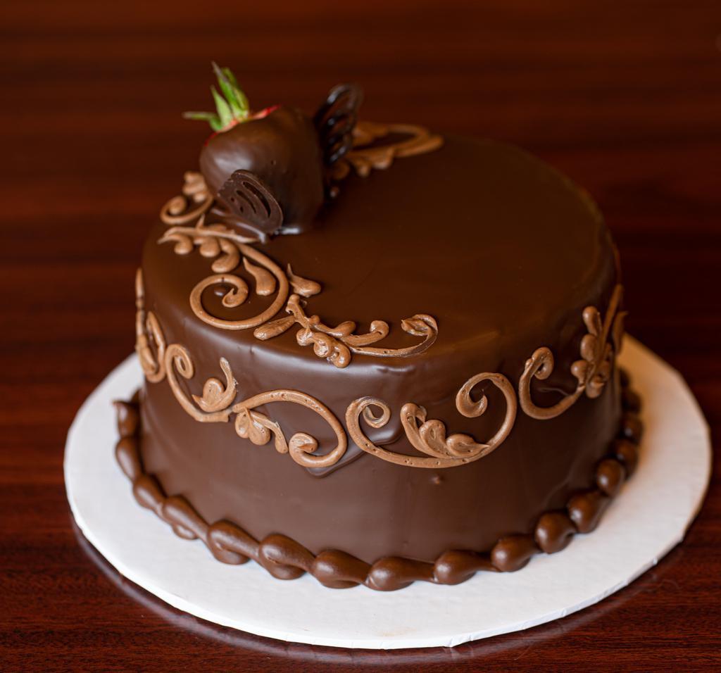 Chocolate Decadence Cake · Rich chocolate cake with a a layer of chocolate mousse and a layer of European chocolate fudge filling, covered in a chocolate buttercream and draped in a dark chocolate ganache.  We top it with 2 strawberries.